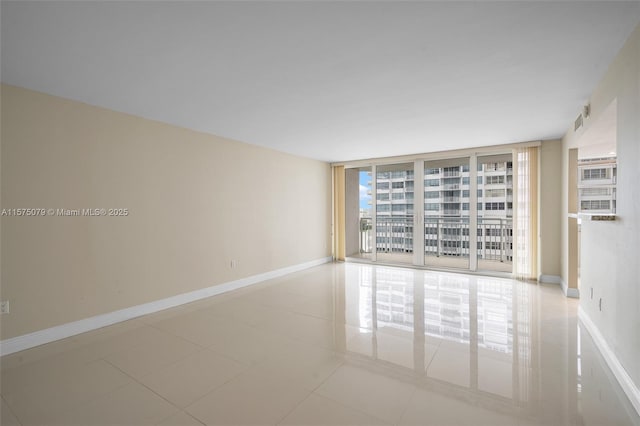 tiled empty room featuring expansive windows and baseboards