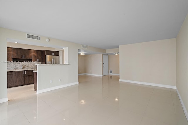 unfurnished living room with visible vents, baseboards, and light tile patterned floors