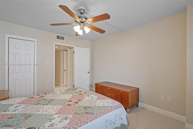 bedroom featuring ceiling fan, light tile patterned flooring, visible vents, baseboards, and a closet