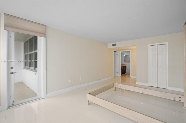 unfurnished bedroom featuring tile patterned flooring, visible vents, and baseboards