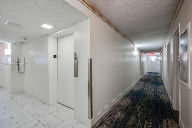 hall featuring a textured ceiling, marble finish floor, visible vents, and baseboards