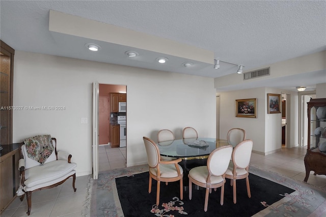 tiled dining room with rail lighting and a textured ceiling