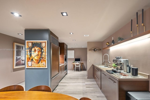 kitchen with sink, light hardwood / wood-style floors, and dark brown cabinets