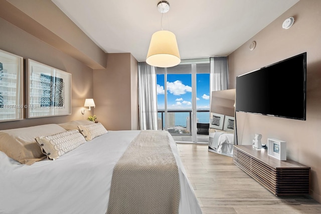 bedroom with access to outside, light hardwood / wood-style flooring, and expansive windows