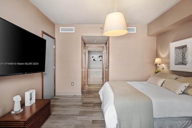 bedroom with hardwood / wood-style flooring and ensuite bathroom