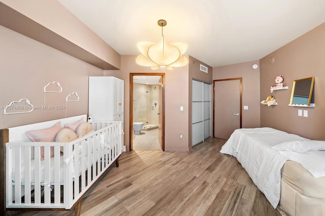 bedroom with light hardwood / wood-style floors and ensuite bathroom