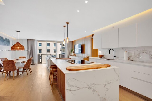 kitchen with white cabinets, light hardwood / wood-style flooring, sink, and a center island