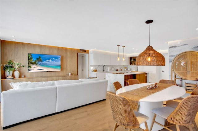 living room with wood walls, light wood-type flooring, and sink