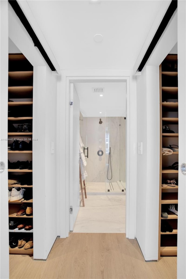 walk in closet with light hardwood / wood-style flooring