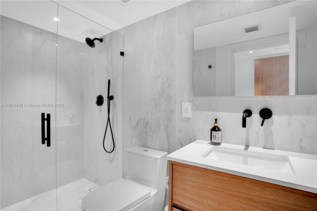 bathroom with tile walls, vanity, toilet, and a shower with shower door