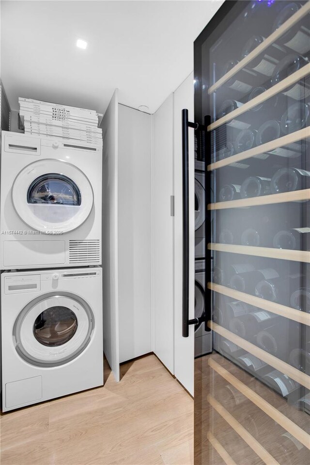 laundry area with light hardwood / wood-style floors, stacked washer and clothes dryer, and wine cooler