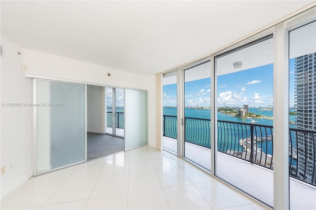 tiled spare room featuring a healthy amount of sunlight and a water view