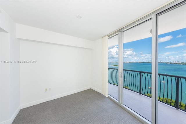 unfurnished room featuring carpet and a water view