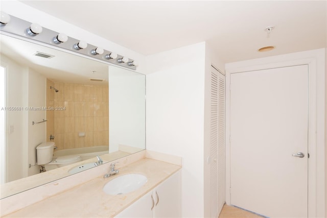 full bathroom with tiled shower / bath combo, oversized vanity, and toilet