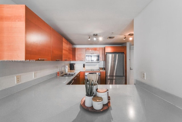 kitchen with kitchen peninsula, sink, rail lighting, and appliances with stainless steel finishes