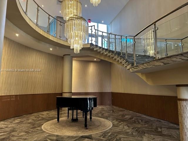 interior space featuring a towering ceiling, wooden walls, and an inviting chandelier