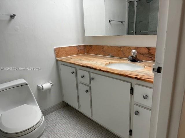 bathroom featuring toilet, tile flooring, and vanity