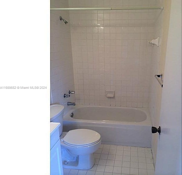 full bathroom featuring tile floors, tiled shower / bath, vanity, and toilet