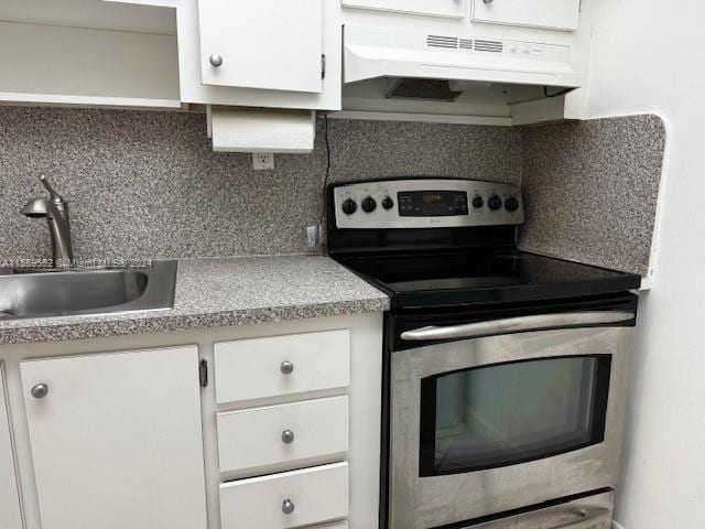 kitchen featuring tasteful backsplash, custom exhaust hood, white cabinets, and stainless steel electric range oven