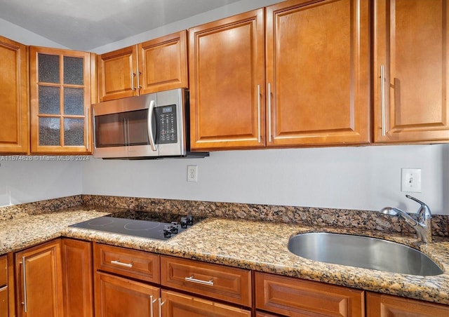 kitchen featuring sink, black electric cooktop, and light stone counters