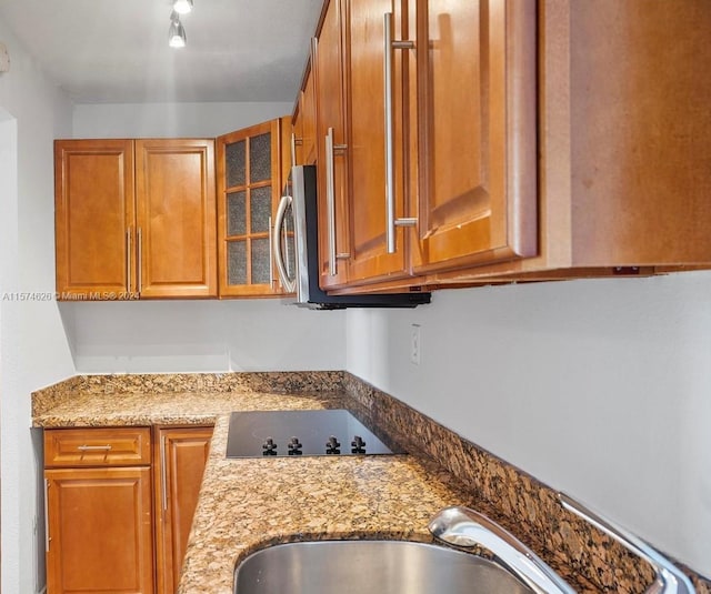 kitchen with sink, rail lighting, black electric stovetop, and light stone countertops