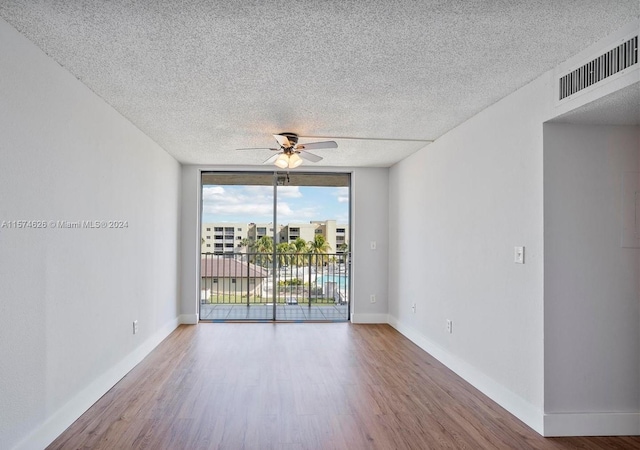 spare room with a wall of windows, a textured ceiling, and hardwood / wood-style floors