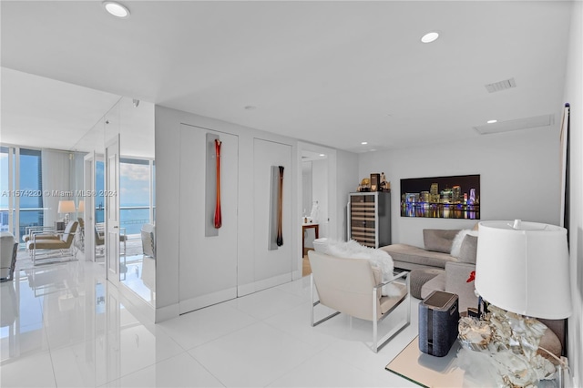 living room featuring floor to ceiling windows, light tile floors, and a water view