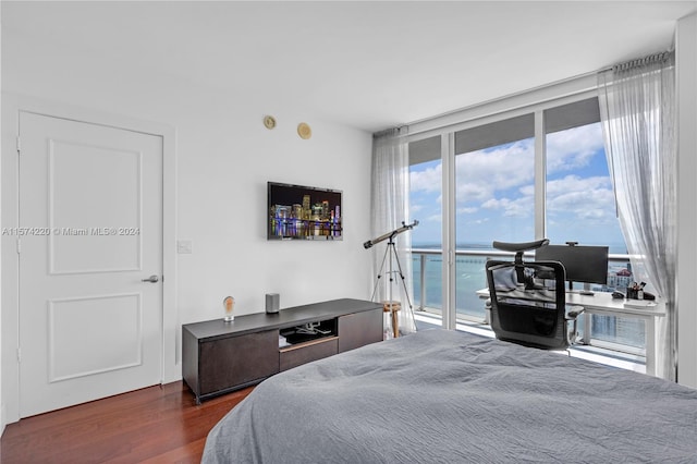 bedroom with a water view, dark hardwood / wood-style floors, and access to outside