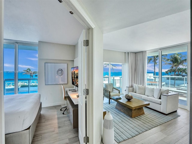 living room featuring light wood-type flooring, floor to ceiling windows, and a water view