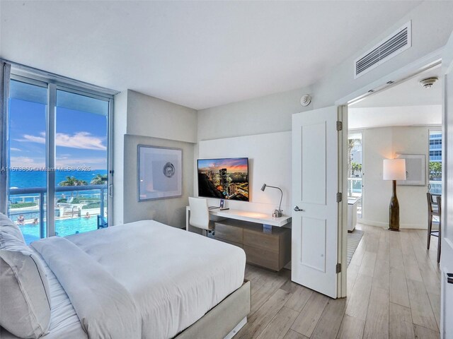 bedroom with light hardwood / wood-style floors and a water view