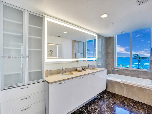 bathroom with vanity and tiled tub