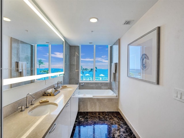 bathroom featuring a relaxing tiled tub and vanity