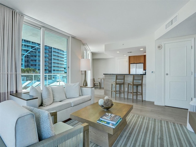 living room with a wall of windows and light hardwood / wood-style flooring