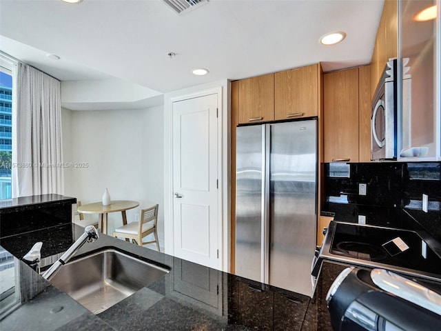 kitchen featuring appliances with stainless steel finishes, dark stone countertops, and decorative backsplash