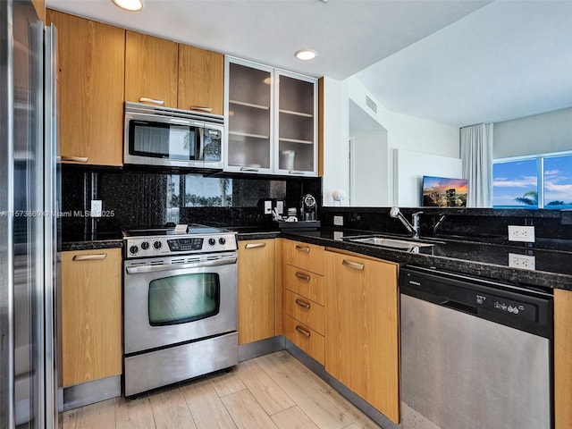 kitchen with backsplash, appliances with stainless steel finishes, sink, and dark stone counters