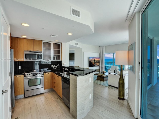 kitchen with sink, stainless steel appliances, kitchen peninsula, and light wood-type flooring