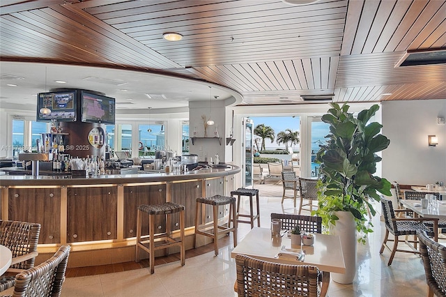 bar with wood ceiling, decorative light fixtures, a healthy amount of sunlight, and light tile patterned flooring