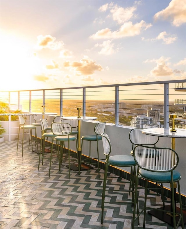 balcony at dusk featuring a patio and an outdoor bar