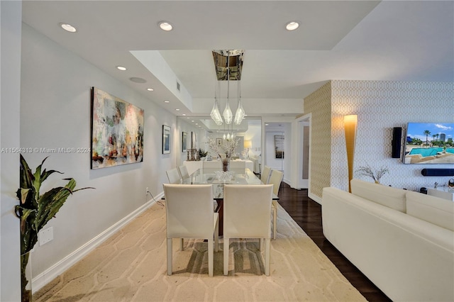 dining area featuring an inviting chandelier, wood-type flooring, and a tray ceiling