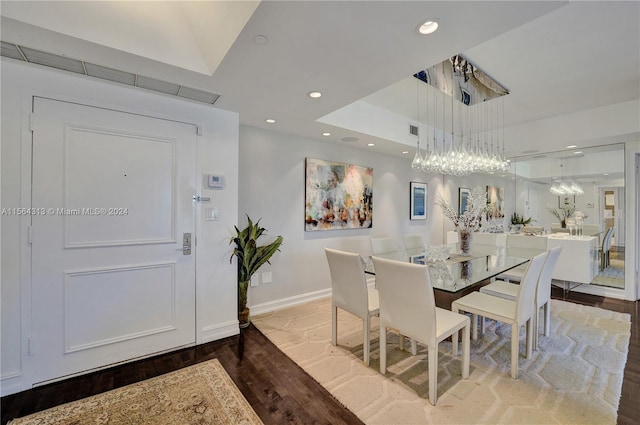 dining space with wood-type flooring and a tray ceiling