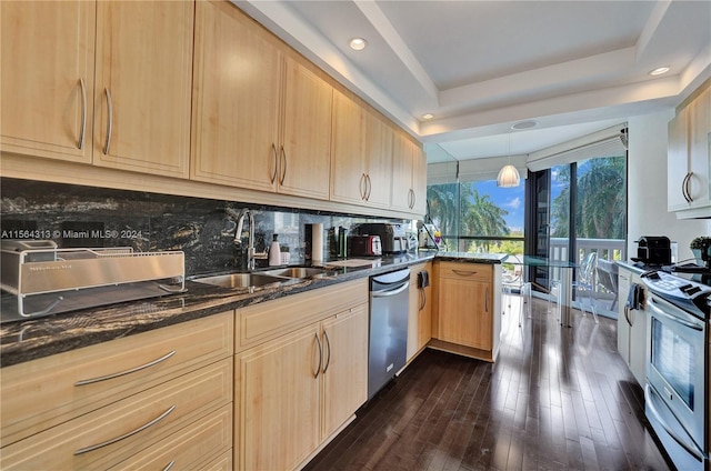 kitchen with appliances with stainless steel finishes, tasteful backsplash, dark wood-type flooring, light brown cabinetry, and a raised ceiling