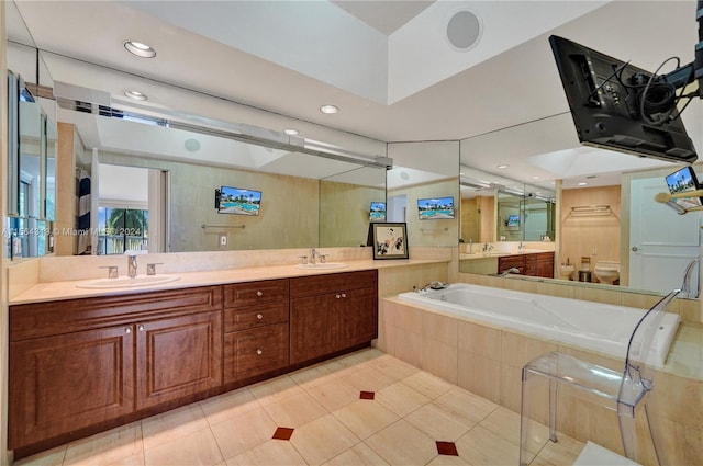 bathroom featuring tiled tub, double vanity, and tile flooring