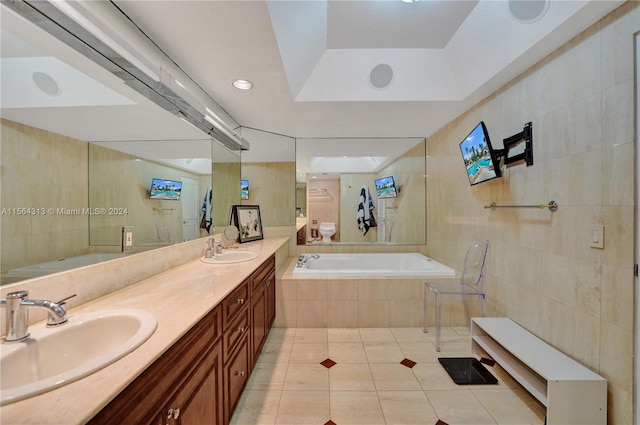 bathroom featuring tile floors, double sink, oversized vanity, a raised ceiling, and tiled bath