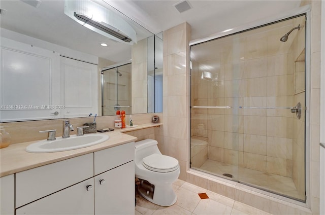 bathroom with tile flooring, tile walls, toilet, a shower with shower door, and vanity