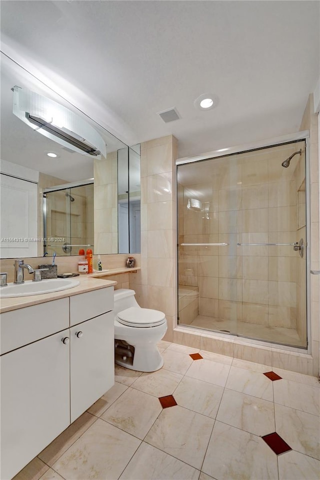 bathroom with walk in shower, tile floors, vanity with extensive cabinet space, and toilet