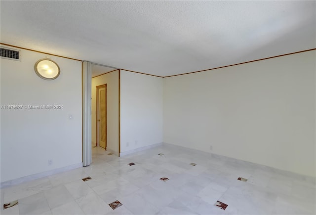 spare room featuring a textured ceiling and light tile flooring