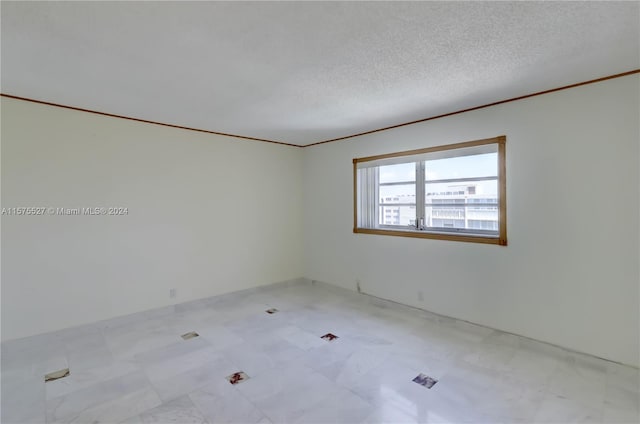 unfurnished room with ornamental molding, tile floors, and a textured ceiling