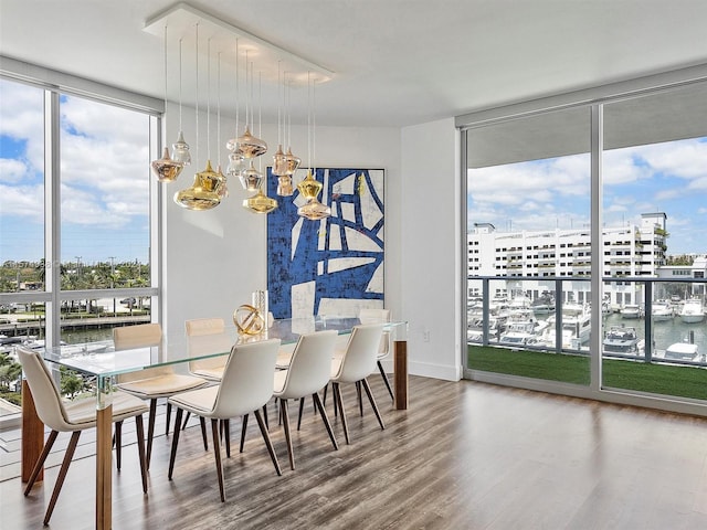 dining area with wood-type flooring, expansive windows, a water view, and an inviting chandelier