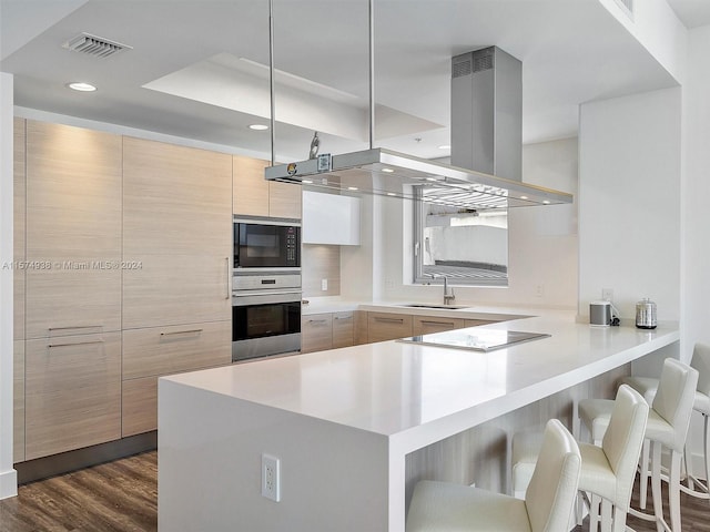 kitchen featuring dark hardwood / wood-style flooring, island range hood, sink, black appliances, and kitchen peninsula