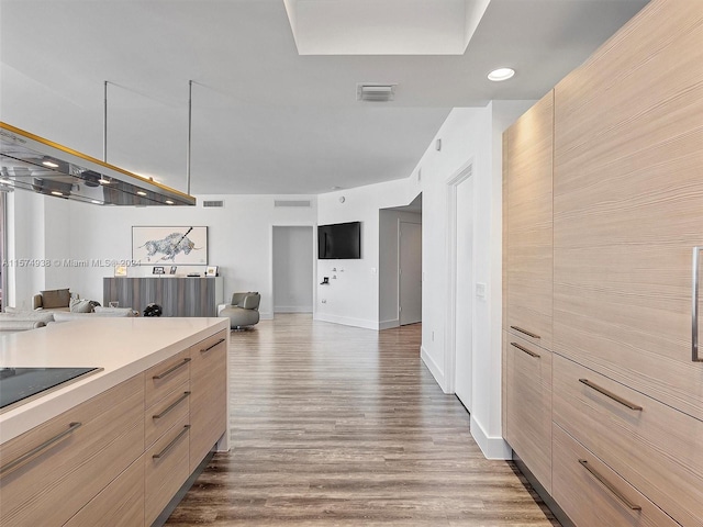 kitchen with black electric stovetop, hardwood / wood-style flooring, and light brown cabinetry